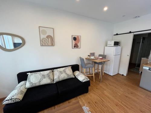 un salon avec un canapé noir et une table dans l'établissement T2 Cosy 700 m de la Grotte, à Lourdes