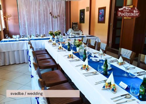 a long table with blue and white tables and chairs at Hotel Podhradie in Považská Bystrica