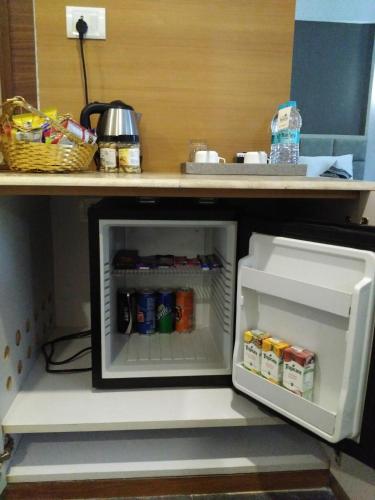 an open refrigerator sitting under a kitchen counter at Maha Bodhi Hotel.Resort.Convention Centre in Bodh Gaya
