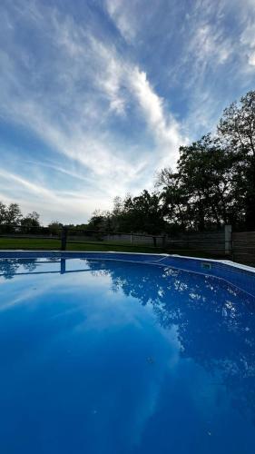 a large blue swimming pool with a cloudy sky at Villa Paradiso in Isola d'Asti