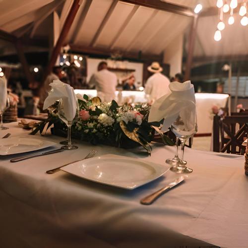a table with white plates and flowers on it at Mikado Natural Lodge in Playa Avellana