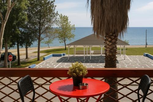 een rode tafel met een palmboom en een prieel bij StudioAretiCom Studio to rent in FRONT the lovely SEA fully equipped plagiastudioseu in Nea Plagia