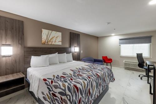 a hotel room with a bed and a red chair at Red Roof Inn Pharr - McAllen in Pharr