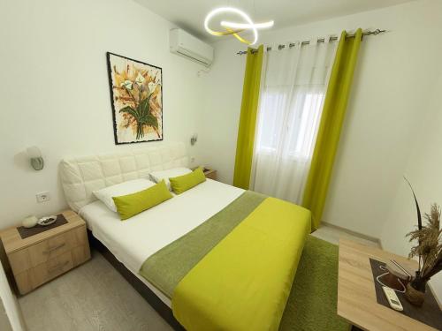 a bedroom with a large bed with yellow and green sheets at Apartmani Avanti Becici in Becici