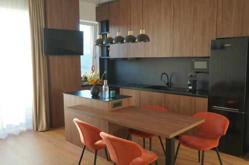 a kitchen with a table and some orange chairs at Urban Grove Apartment with Balcony and Free Parking in Floreşti