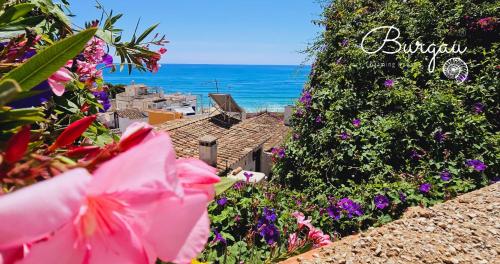 a view of the ocean from a garden with flowers at Burgau Charming House Loft in Burgau