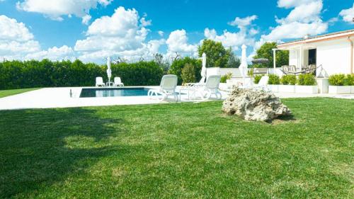 een tuin met stoelen en een zwembad bij Villa Menea con Piscina e Spa nel Salento in Casarano
