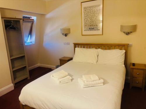 a bedroom with a bed with two towels on it at Rothwell House Hotel in Kettering