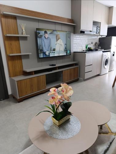 ein Wohnzimmer mit Fernseher und einem Tisch mit Blumen in der Unterkunft Hermoso Apartamento con piscina in La Playa Bejarano