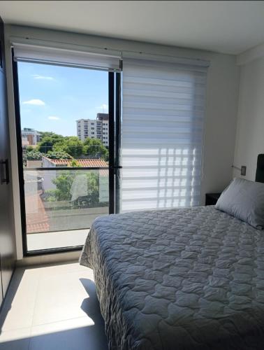 ein Schlafzimmer mit einem Bett und einem großen Fenster in der Unterkunft Hermoso Apartamento con piscina in La Playa Bejarano