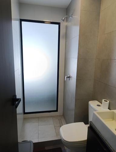 a bathroom with a toilet and a glass shower door at Hermoso Apartamento con piscina in La Playa Bejarano
