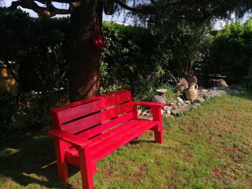 a red bench sitting in the grass next to a tree at B&B La Casa di Rita in Castrezzato