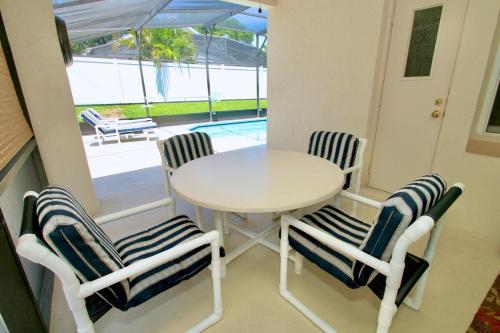 a white table and four chairs with an umbrella at Family Escape Close to parks in Orlando