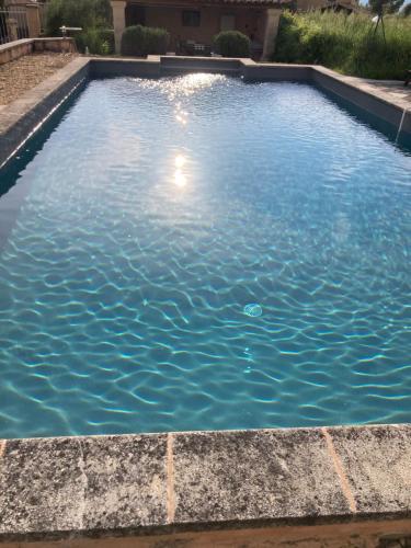 a swimming pool with blue water in a yard at La Tanière du Ventoux in Bédoin