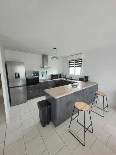 - une cuisine avec un comptoir et deux tabourets dans l'établissement La Bohème, à Guilmécourt
