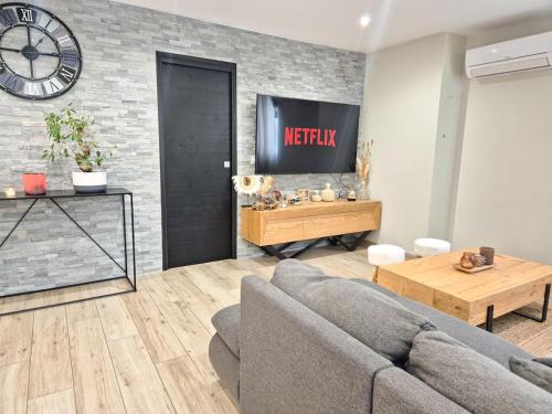 a living room with a couch and a clock on a brick wall at Villa Élégante à Berre-les-Alpes - Terrasse, Piscine & Vue Panoramique in Berre-les Alpes