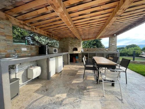 an outdoor kitchen with a table and chairs under a wooden ceiling at Villa Élégante à Berre-les-Alpes - Terrasse, Piscine & Vue Panoramique in Berre-les Alpes
