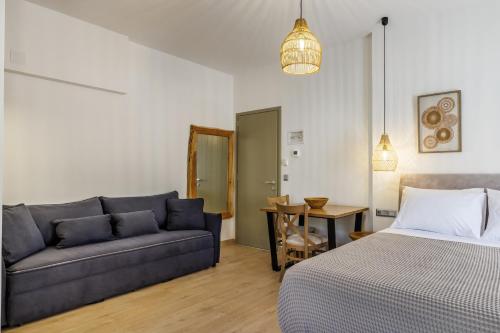 a bedroom with a bed and a couch and a table at Skopelos Prime Central Stays in Skopelos Town