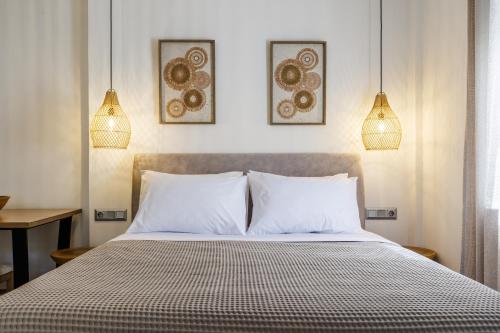a bedroom with a bed with white pillows and two lights at Skopelos Prime Central Stays in Skopelos Town