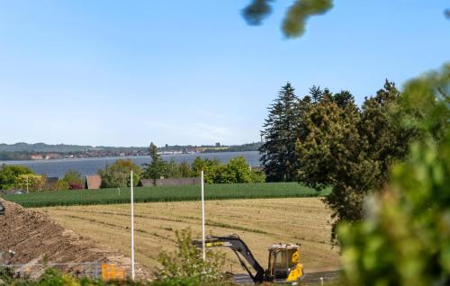 a yellow bulldozer in a field next to the water at 3 Bedroom Awesome Home In Kalvehave in Kalvehave