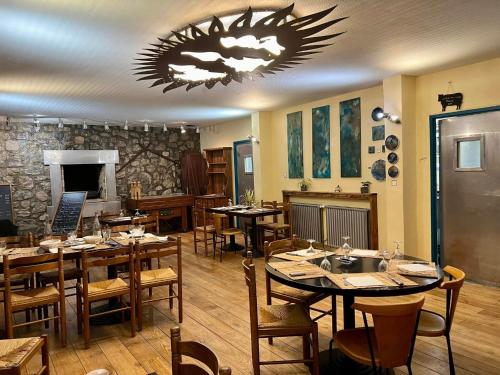 a restaurant with tables and chairs and a chandelier at Le Boréal in La Bastide-de-Sérou