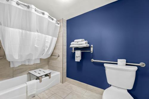 a bathroom with a white toilet and a blue wall at Spark By Hilton Biloxi Ocean Springs in Biloxi