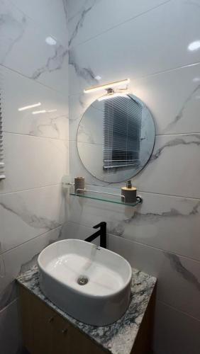 a white bathroom with a sink and a mirror at Keylah Guest House in Cotonou
