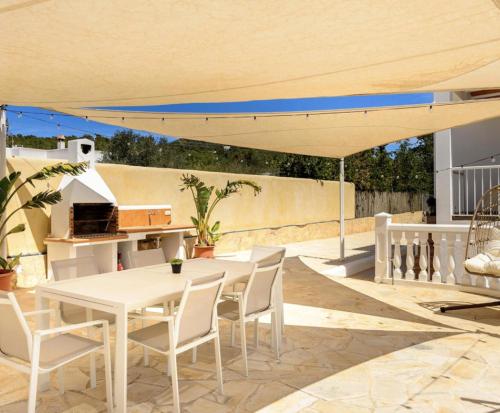 a patio with a white table and chairs under a umbrella at Villa Prats Ibiza in Sant Josep