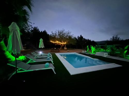 a swimming pool with lounge chairs and umbrellas at night at Villa Prats Ibiza in Sant Josep