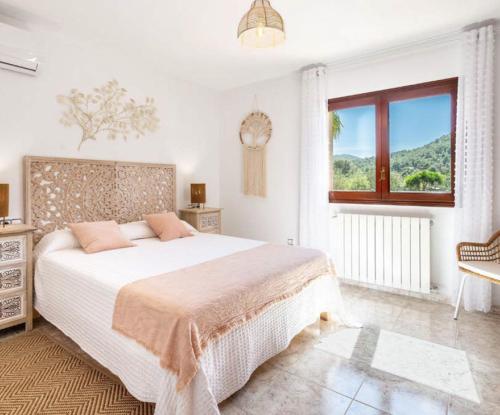 a white bedroom with a large bed and a window at Villa Prats Ibiza in Sant Josep