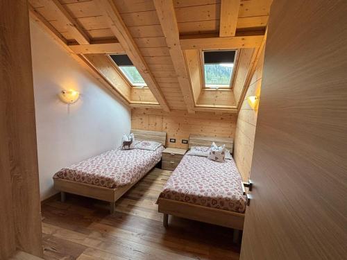 two beds in a small room with two windows at Appartamenti Daberto Fabiola in Arabba