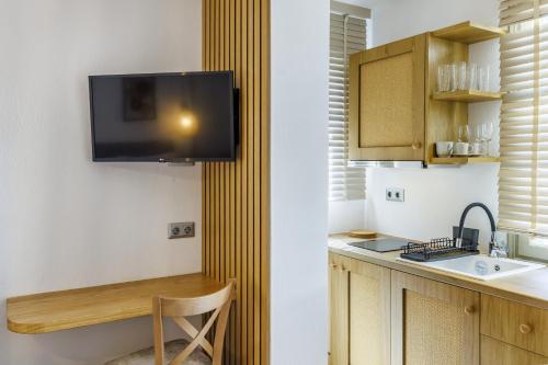 a kitchen with a sink and a tv on a wall at Skopelos Prime Central Stays in Skopelos Town