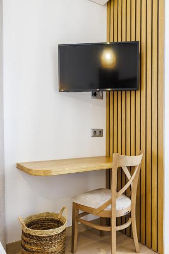 a tv on a wall with a wooden table and a chair at Skopelos Prime Central Stays in Skopelos Town