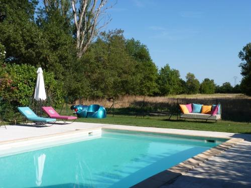 a swimming pool with two chairs and an umbrella at Domaine de Rhodes B&B in Avignon