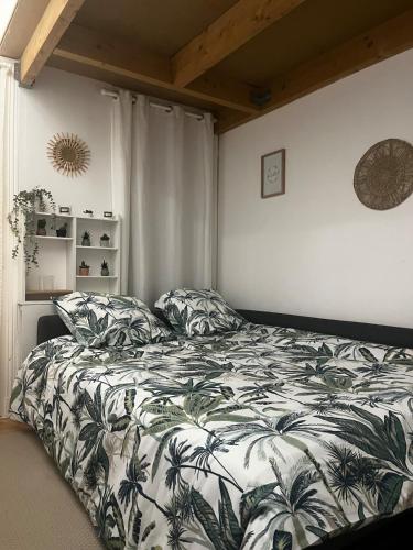 - une chambre avec un lit et une couverture à motifs de feuilles dans l'établissement Le Cosy Champenois! Reims Arena, à Reims