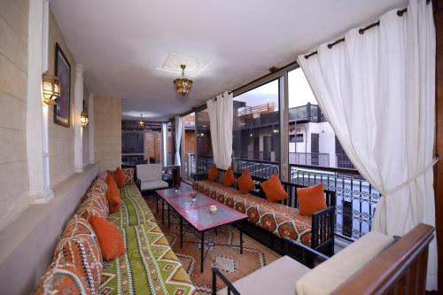 a balcony with couches and tables and windows at RIAD KALE POLIS in Marrakech