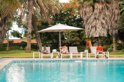 a group of people sitting under an umbrella next to a pool at Holiday Inn - Bulawayo by IHG in Bulawayo