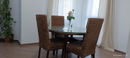 a glass table with three chairs and a vase with flowers at Residence Debbabi sans coupure d'eau in Monastir