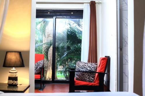 a room with a window and a red chair in a room at Gold Palm Hotel in Gulu