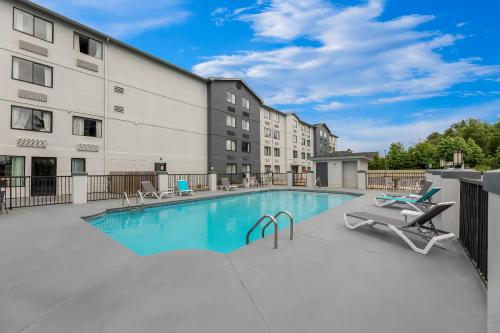 a swimming pool with chairs and a building at Spark By Hilton Biloxi Ocean Springs in Biloxi