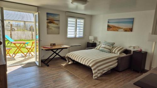 a bedroom with a bed and a table and a patio at Crevette rose à 100m de la plage de sable de Surtainville in Surtainville