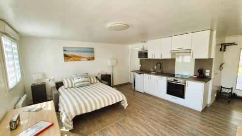a living room with a bed and a kitchen at Crevette rose à 100m de la plage de sable de Surtainville in Surtainville