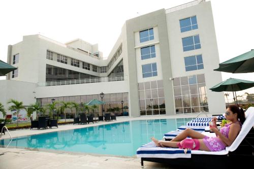 a young girl sitting on a chair next to a swimming pool at Maha Bodhi Hotel.Resort.Convention Centre in Bodh Gaya
