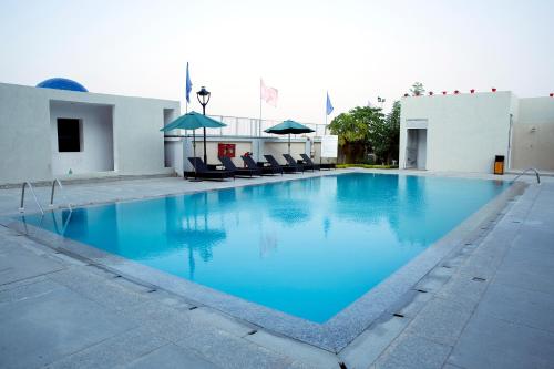 a large blue pool with chairs and umbrellas at Maha Bodhi Hotel.Resort.Convention Centre in Bodh Gaya