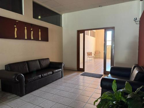 una sala de espera con 2 sofás de cuero y una mesa en Hotel Marney Aguascalientes, en Aguascalientes