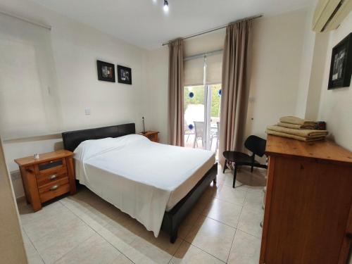 a bedroom with a bed and a desk and a window at Villa Arfa in Peyia