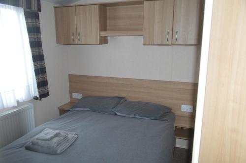 a bedroom with a bed and wooden cabinets at B4 at The Old Mill Holiday Park in Dyke