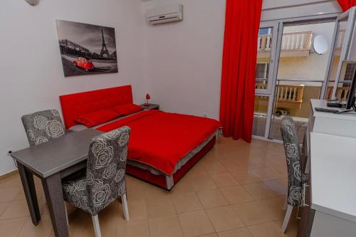 a bedroom with a red bed and a table and chairs at Vanila Apartmani in Sutomore