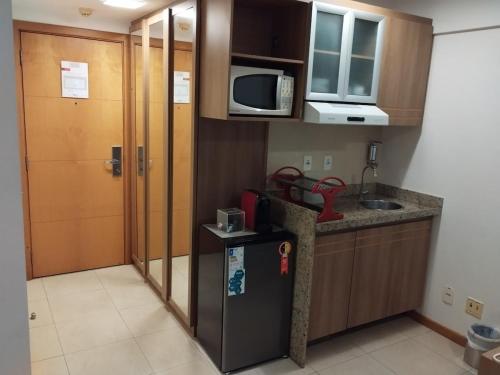 a small kitchen with a refrigerator and a microwave at Apart no Hotel Saint Moritz n° 810 in Brasilia