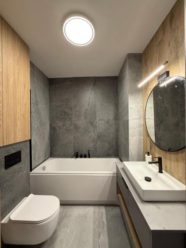 a bathroom with a tub and a toilet and a sink at Czyżyk - Apartamenty Rydzewo in Rydzewo